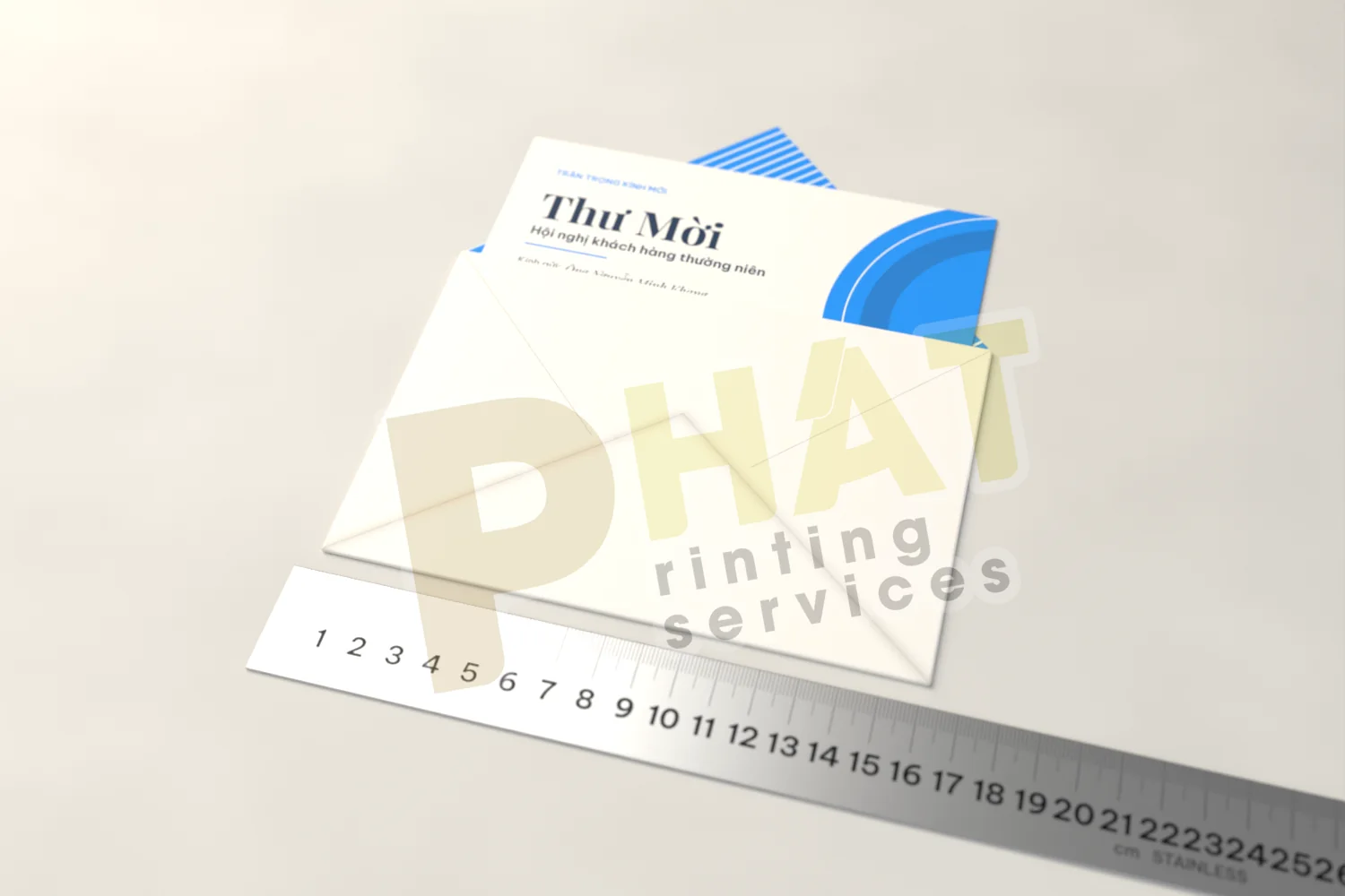 Thư mời dáng ngang 15 × 10 cm rút ra khỏi bao thư mở nắp, đặt trên thước thép để đo khoảng hở