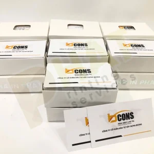 Nhiều hộp đựng name card dán nhãn logo công ty, phía trước là hai tấm name card cùng mẫu