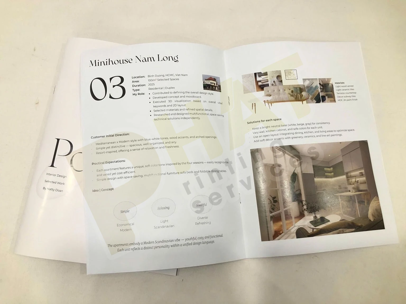 Cuốn portfolio bìa trắng mở ra ở trang có ảnh phối cảnh phòng và đoạn chú thích