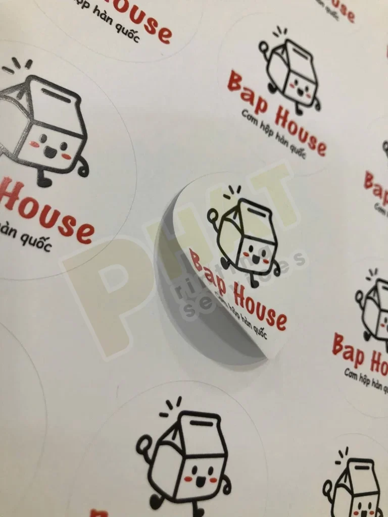 Tờ tem nhãn tròn in logo đỏ đen, một con tem đang được bóc lên khỏi lớp đế