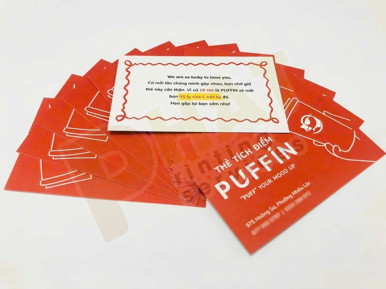 In Voucher Có Số Sê-ri Và Mã QR: Chuẩn Bị Dữ Liệu Và Kiểm Trùng 3 Nhiều thẻ tích điểm nền cam trải trên bàn, một thẻ lật thấy mặt sau có lời nhắn
