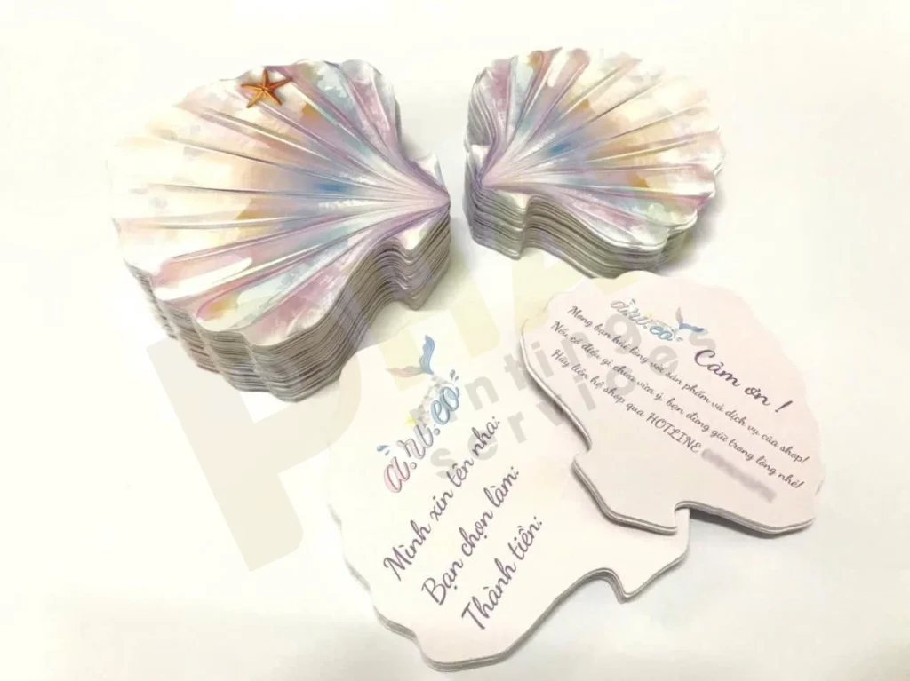 Ấn Phẩm Gói Hàng Shop Online: Bộ Tag, Sticker, Thank You Card 1 Hai xấp thiệp bế hình vỏ sò ánh xà cừ và vài tấm thiệp cảm ơn đặt phía trước