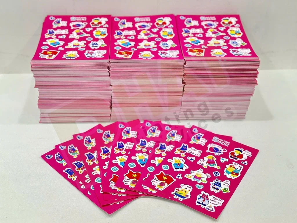 Nhiều xấp tờ sticker nền hồng xếp chồng, phía trước là các tờ trải hình quạt